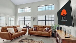 Ein geräumiges Wohnzimmer mit zwei braunen Ledersofas, einem Holztisch und einem großen Teppich.