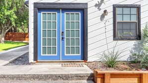 Ein Haus mit einer blauen Doppeltür, einem kleinen Fenster und einem hölzernen Blumenkasten davor.