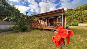 A wooden cabin with a balcony, surrounded by lush greenery and a clear sky.