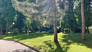 A park with a paved path, green grass, and tall trees. - 3 rooms equipped all comfort with swimming pool and tennis near the navigli (Milano)