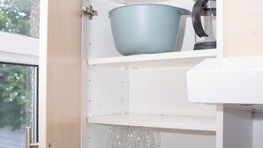 Eine Küche mit weißen Schränken, einer blauen Schüssel, einem Wasserkocher und einer Vase mit Tulpen.