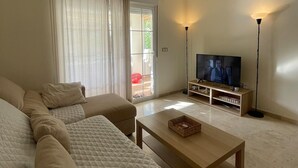 Ein Wohnzimmer mit einer Sofagarnitur, einem Couchtisch, einem Fernseher und zwei Stehlampen.