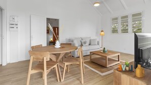 A modern living room with a wooden dining table, chairs, a sofa, and a fireplace. - Kaza 3 Anses - Two Bedroom Villa, Sleeps 6 (Sainte-Anne)