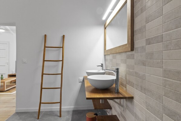 A bathroom with a wooden ladder, a white sink, and a mirror on a tiled wall.