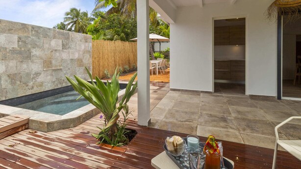 A modern outdoor patio with a hot tub, wooden deck, and a dining area with a table and chairs. - Kaza 3 Anses - Two Bedroom Villa, Sleeps 6 (Sainte-Anne)
