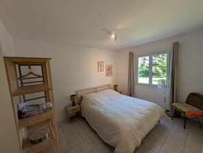 Una camera da letto con un letto, comodini, un'armadiatura in legno, una finestra con vista e una luce a soffitto.