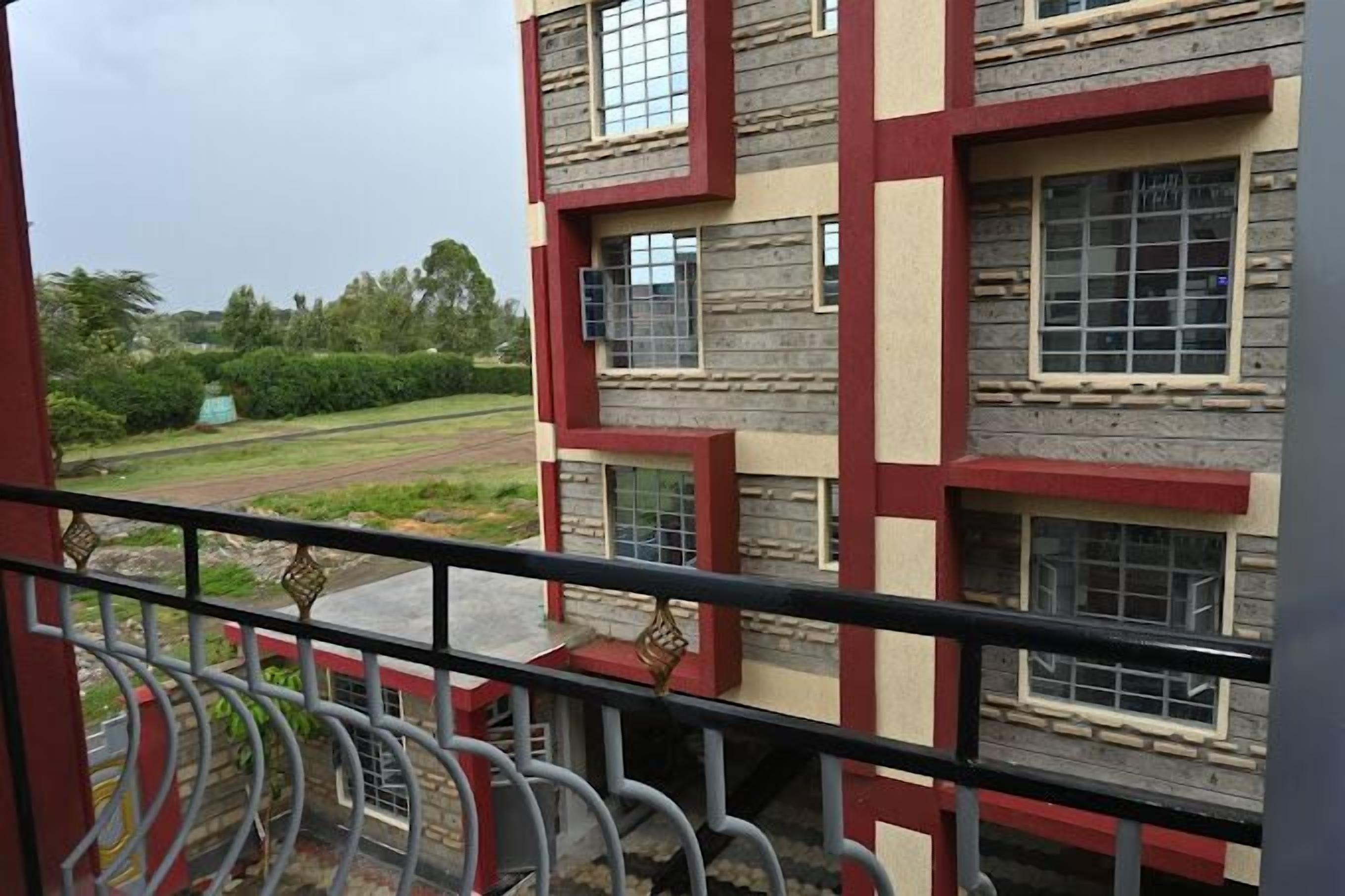 A multi-story building with a balcony, featuring a combination of stone and red framing.