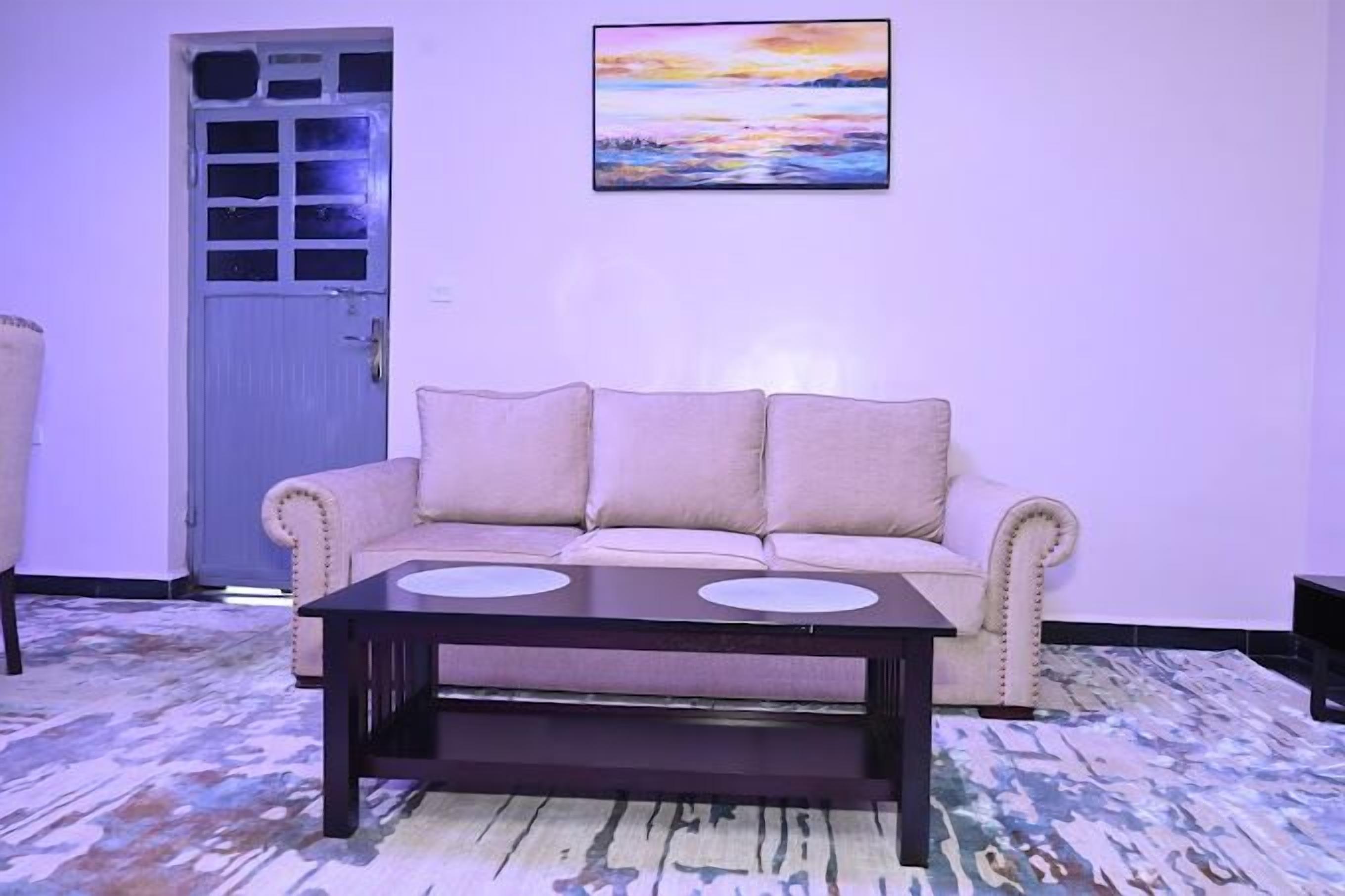 Un salon avec un canapé beige, une table basse en bois foncé et un tableau abstrait aux couleurs vives accroché au mur.