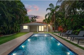 A swimming pool with a house in the background, surrounded by greenery. -  Villa Miami Poolside Paradise (Miami)