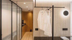 Un baño moderno con tocador de madera, un perchero con toallas blancas y un libro en la encimera.