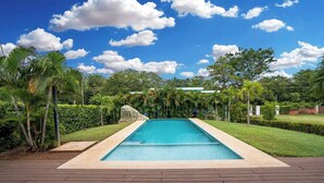 A rectangular swimming pool with a clear blue water surface, surrounded by a paved deck. - Modern Home with Lush Mountain Views and Spectacular Shaded Terrace in Private Gated Community (Playa Potrero)