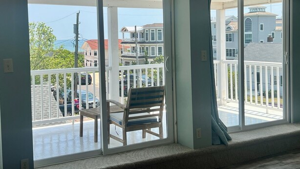 A balcony with a view of neighboring houses and a parked car.