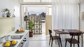 A modern kitchen with a dining area, featuring a white countertop, a stove, and a dining table with chairs. - Blackbrick Hotel Gardens - Cape Town (Cape Town)