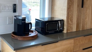 A kitchen with a coffee maker, microwave, and wooden cabinets. - The Northern Tickle. 20 minutes to Twillingate. Gorgeous views of the ocean. (Summerford)