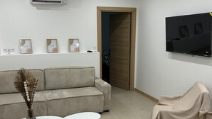 Una sala de estar moderna con un sofá, una mesa de centro, un televisor montado en la pared y un equipo de aire acondicionado.