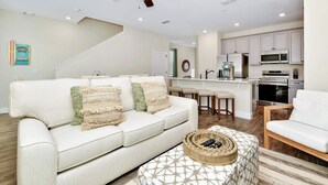 Uma sala de estar moderna com sofá, banqueta e ventilador de teto.