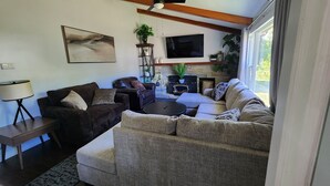 A living room with a fireplace, two sofas, a coffee table, and a TV mounted on the wall. - Relax in Comfort! (Cornwall)