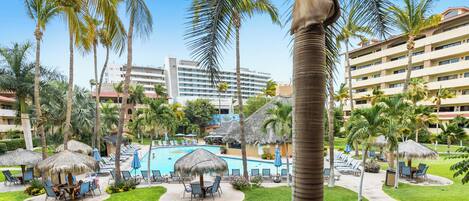 A resort with a swimming pool, palm trees, and lounge chairs.
