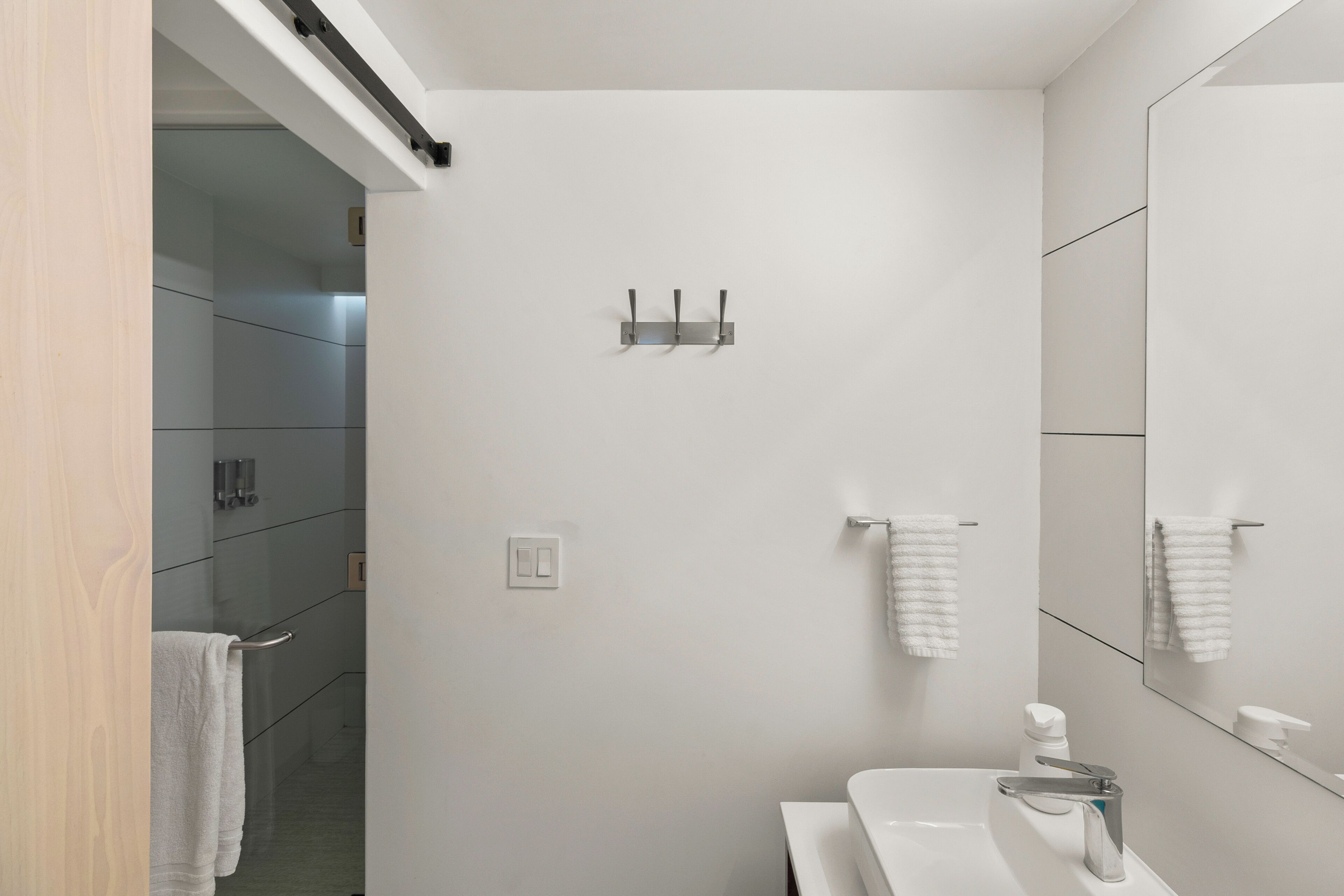 A modern bathroom with a white sink, a mirror, and a towel rack.