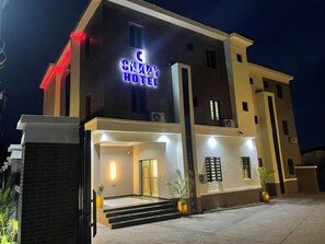 A hotel with a prominent sign, a well-lit entrance, and a staircase leading to the door. - Chapy hotel and suite (Enugu)