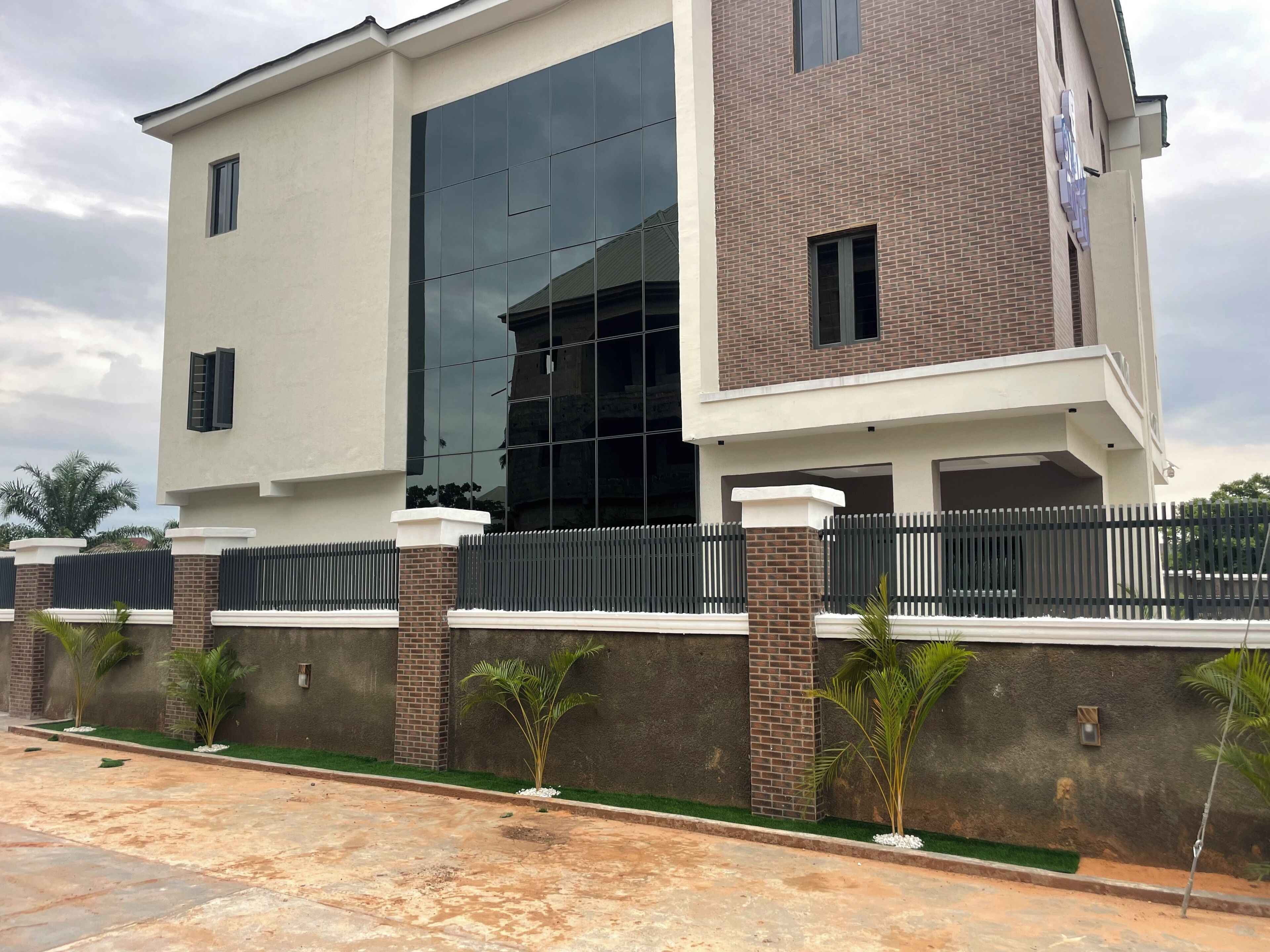 A modern two-story building with a large glass facade, a brick section, and a gated entrance.
