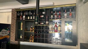 Eine Bar mit Regalen voller Flaschen und Gläsern, einer Hängelampe und einer Ziegelwand.