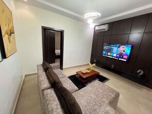 A modern living room with a sectional sofa, a coffee table, and a flat-screen TV mounted on a dark wall. - Chapy hotel and suite (Enugu)