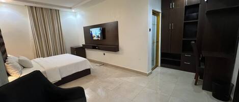 Una habitación de hotel con cama, televisión, armario y zona de estar.