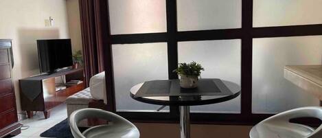 Une pièce comprenant une télévision, une petite table avec une plante, deux chaises, un canapé et un meuble.