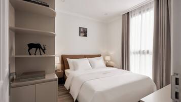 Een hotelkamer met een bed, nachtkastjes, een boekenkast en een raam met gordijnen.