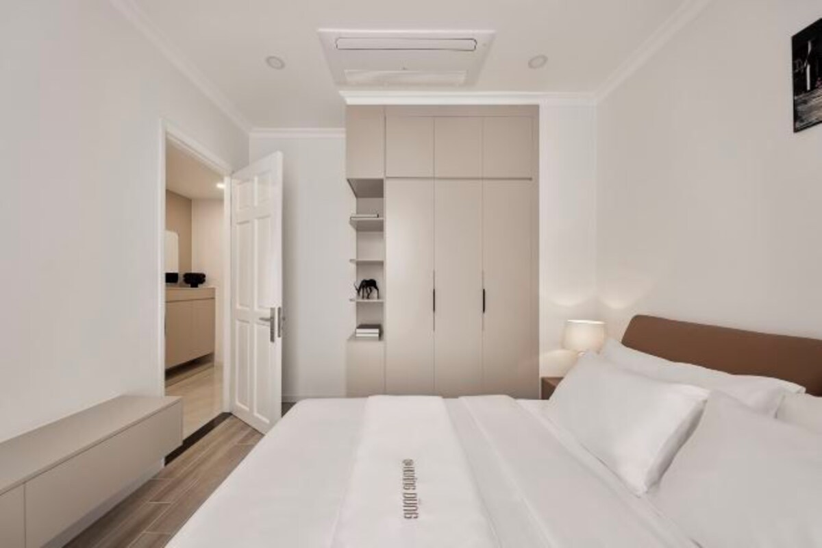 A modern bedroom with a bed, a wardrobe, and a bedside table with a lamp.