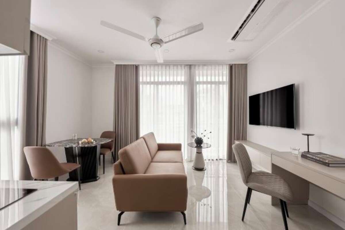 Una sala de estar moderna con un sofá, una mesa de comedor y un televisor montado en la pared.