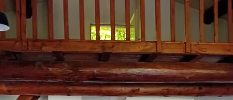 Un coin repas avec une table et des chaises en bois, une cheminée et un balcon doté d’une balustrade en bois.