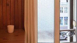 A room with wooden walls, a glass door, and a view of a street with buildings.