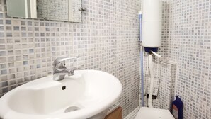 A bathroom with a white sink, a mirror, and a tiled wall.