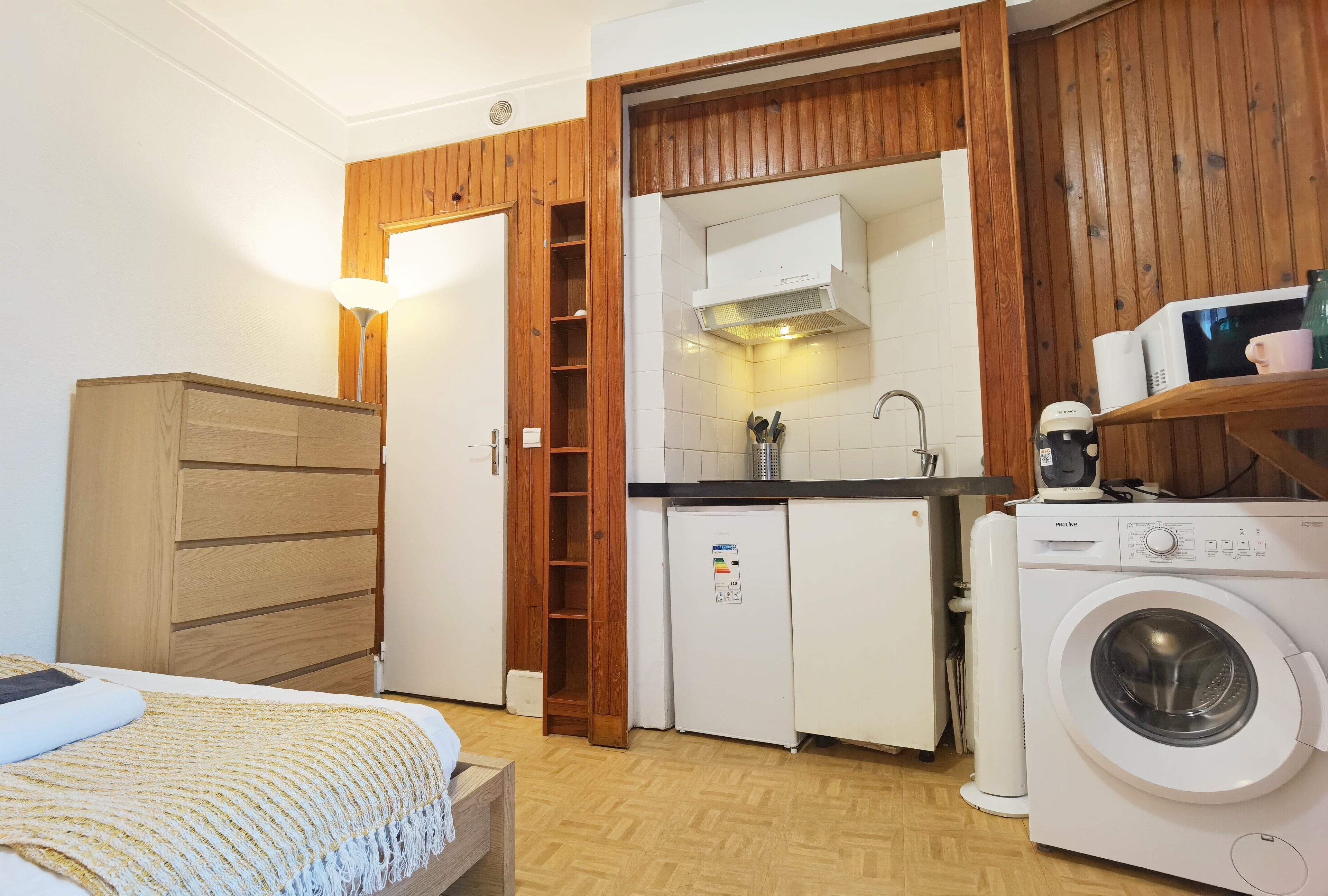Una cocina compacta con microondas, refrigerador y lavadora.