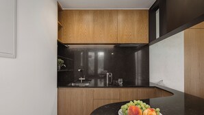 Una cocina moderna con armarios de madera, encimera negra y un plato de fruta.