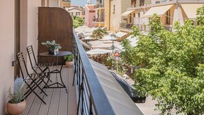 Un balcón con mesa y sillas, plantas en macetas y vista a la ciudad.