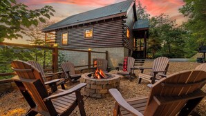 A log cabin with a fire pit and Adirondack chairs in the outdoor seating area.