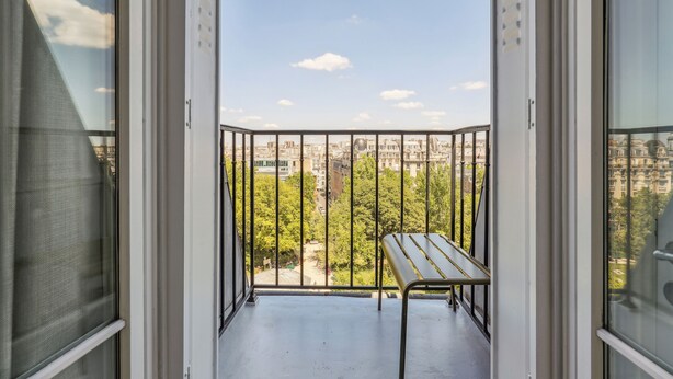 A balcony with a metal table and a view of a cityscape. - Charming 1BR in Le Marais - Bretagne (Paris)
