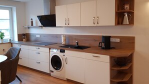 Cocina compacta con lavadora, cafetera y lavabo.