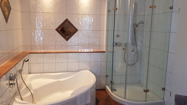 A bathroom with a bathtub, a glass-enclosed shower, and a vanity with a mirror.