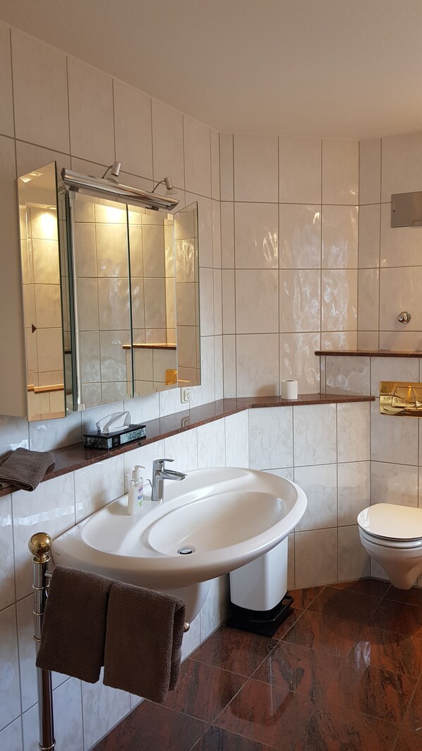 Een moderne badkamer met een grote spiegel, een wastafel en een toilet.