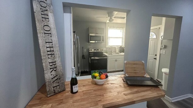 Una cocina con encimera de madera, un cuenco de fruta y una botella de vino.