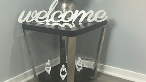 Una mesa en esquina con un letrero que dice 'welcome', una lámpara y dos figuras decorativas.