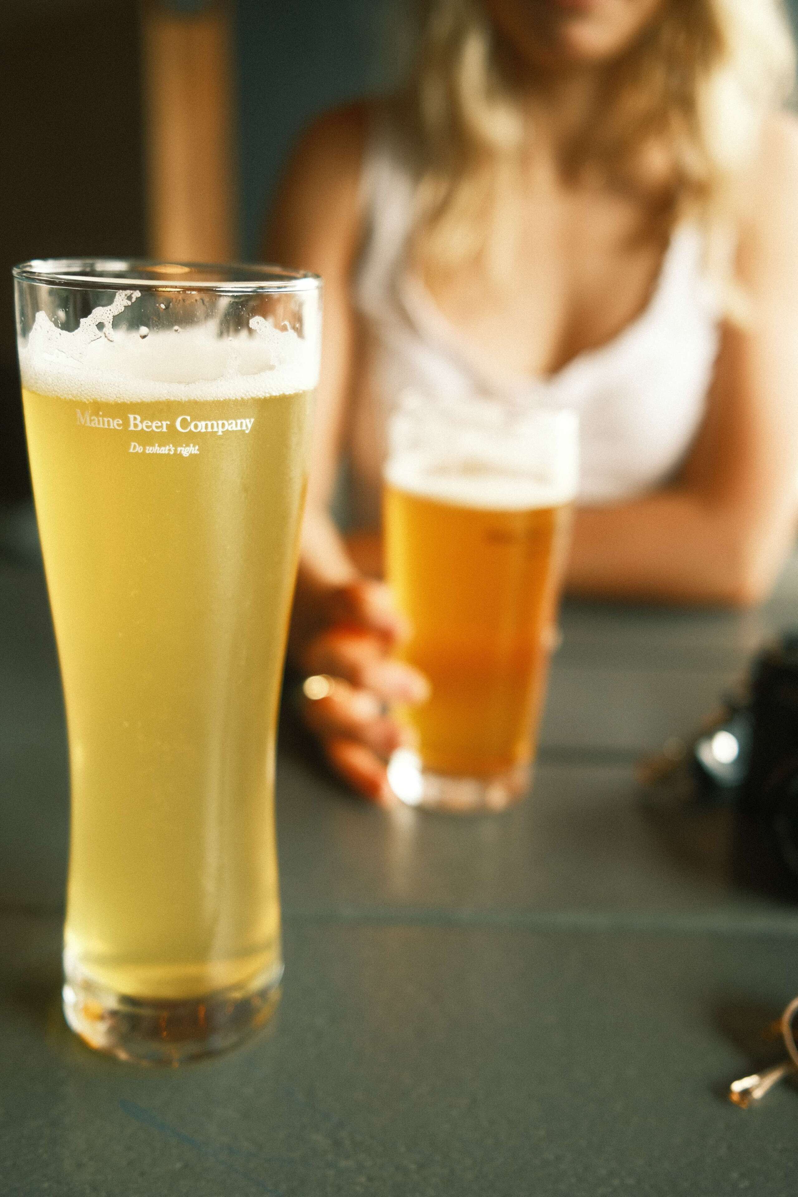 Two glasses of beer on a table.