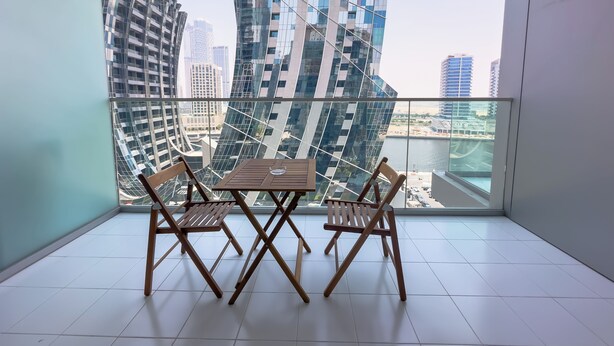 Un balcon donnant sur des immeubles modernes, avec une table et des chaises.