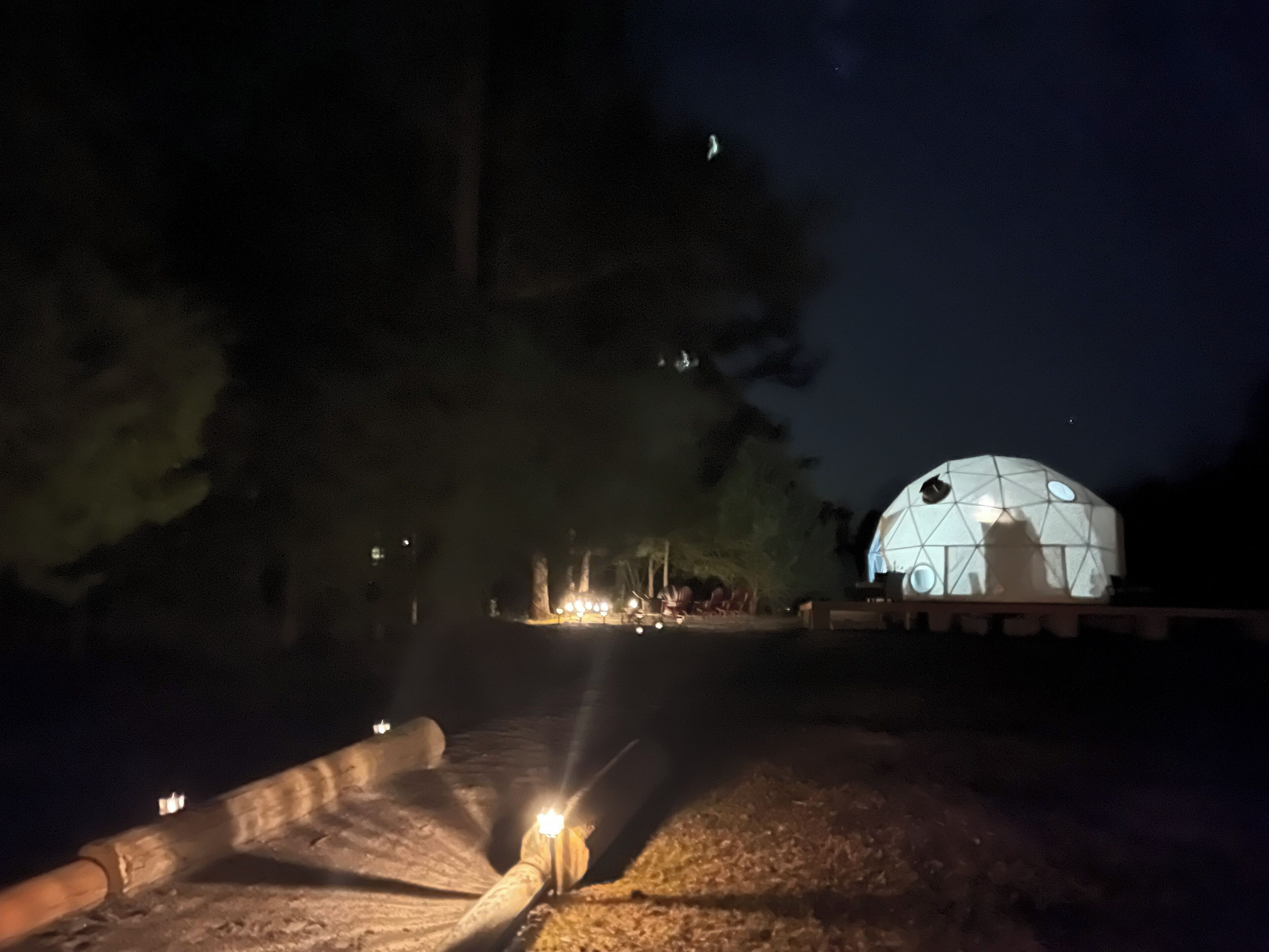 Un bâtiment en forme de dôme, orné d’un motif géométrique, entouré d’arbres et accessible par un sentier.