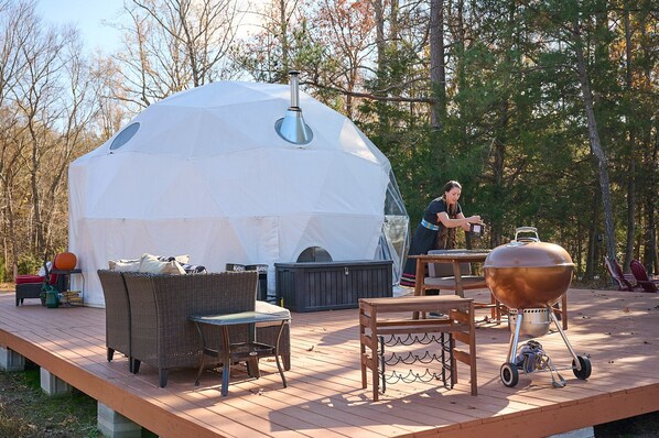 A covered outdoor area with a tent, wicker furniture, a barbecue grill, and a hot tub.