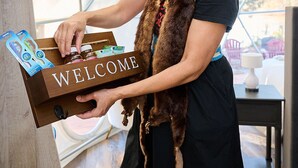 Une personne tenant une boîte en bois sur laquelle est inscrit le mot « BIENVENUE ».
